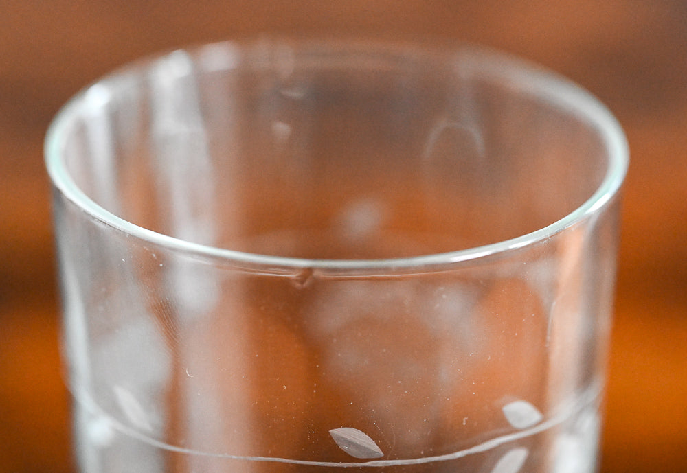clear juice glass etched with grapes on wood table