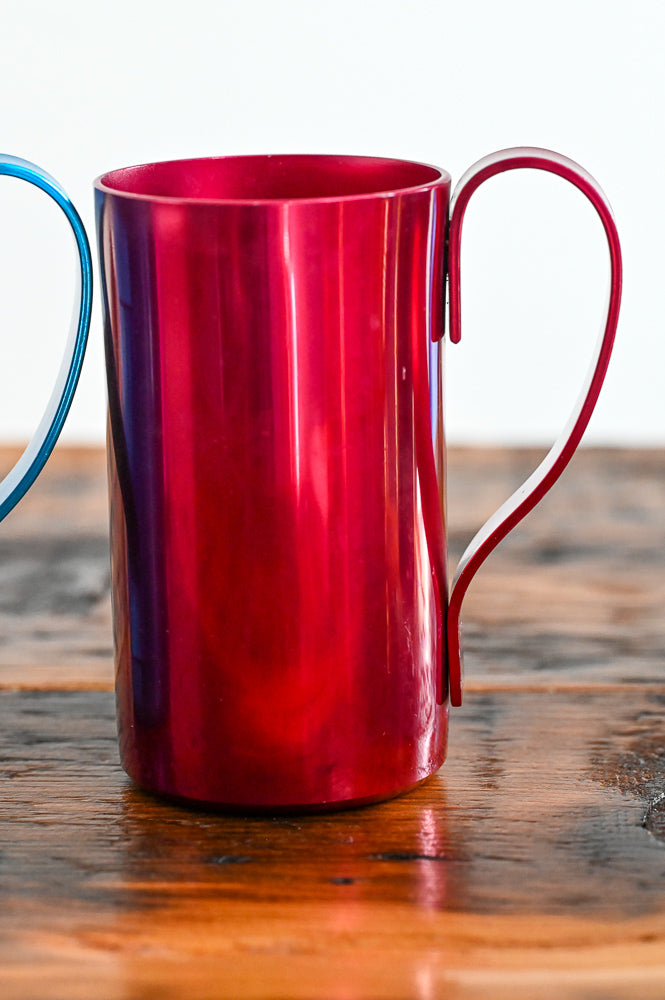 red metal mug on wooden table