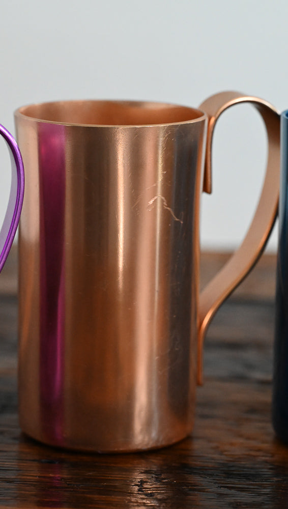 gold metal mug on wooden table