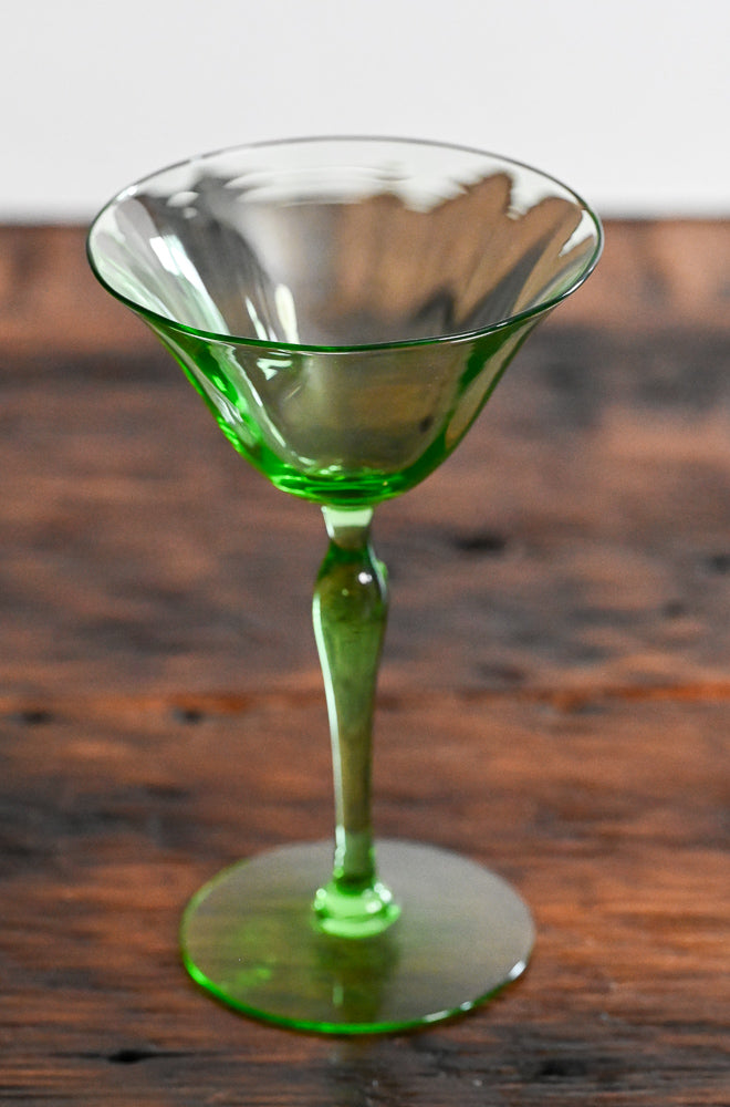 green coupe glass on wooden table