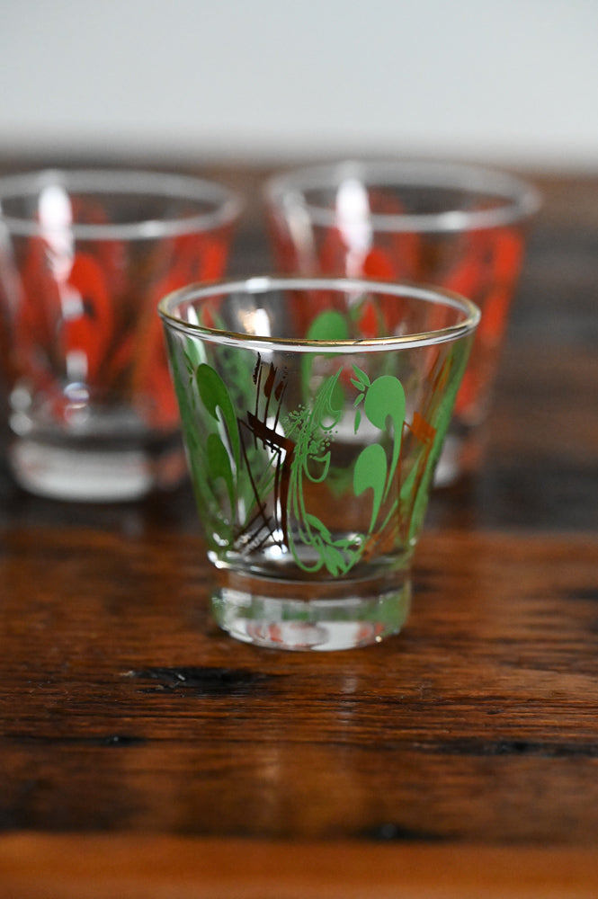 green and gold MCM lowball glass, orange and gold MCM lowball glasses in background