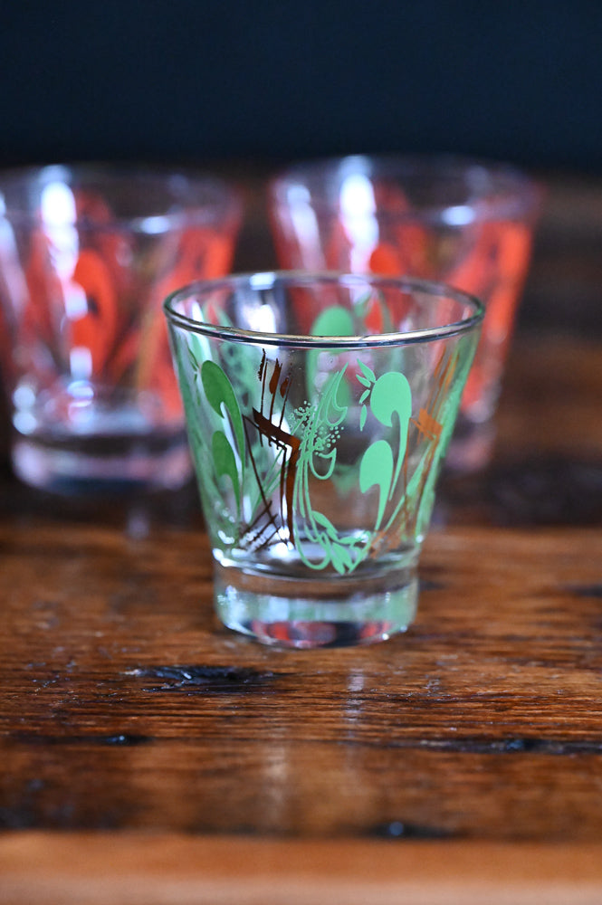 green and gold MCM lowball glass, orange and gold MCM lowball glasses in background