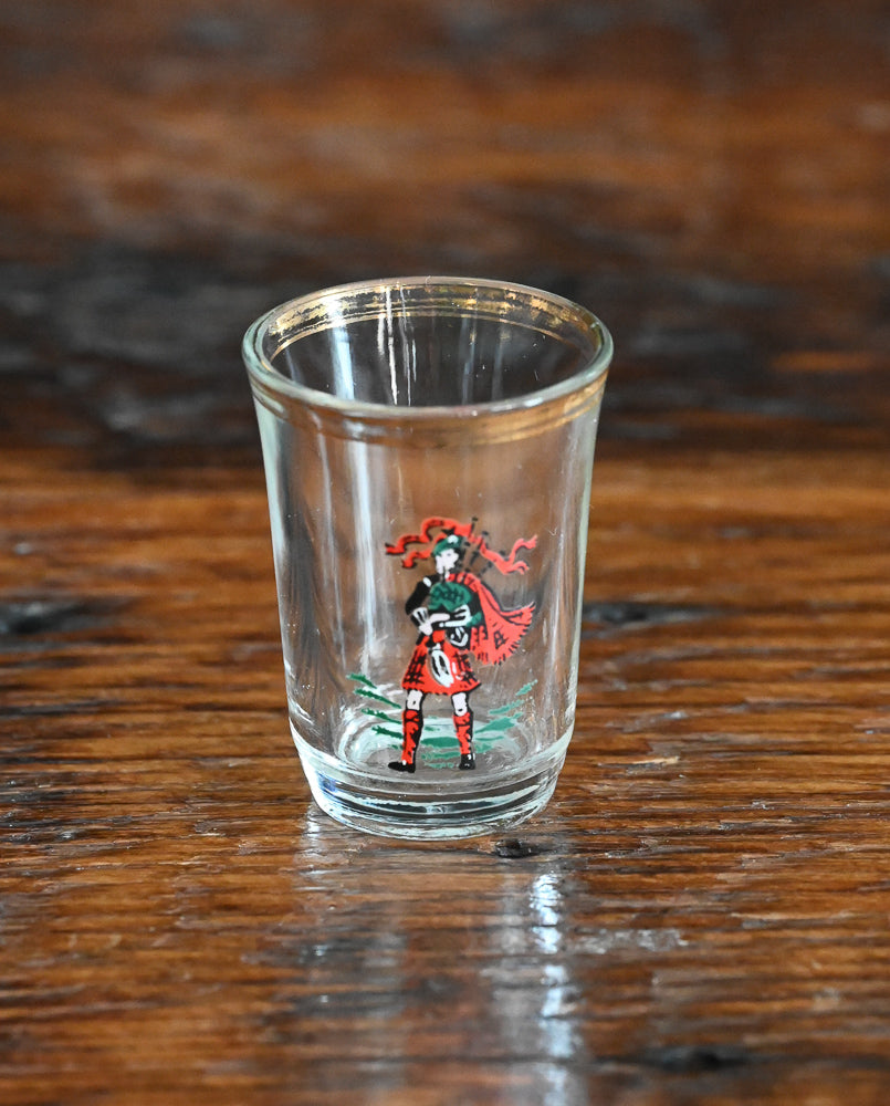 red kilted bagpiper on shotglass with gold rim