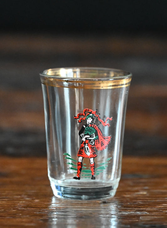 red kilted bagpiper on shotglass with gold rim