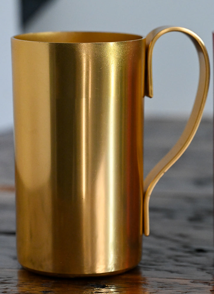gold metal mug on wooden table