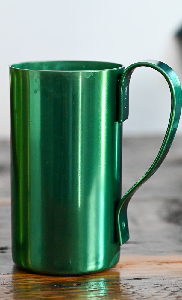 green metal mug on wooden table