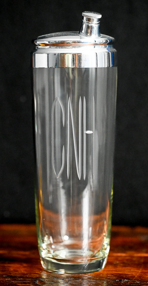 Clear glass cocktail shaker monogrammed with "CNH", metal lid