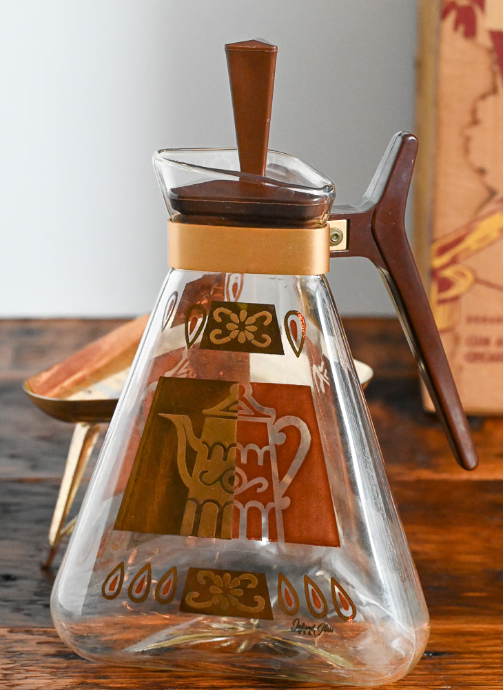 brown and gold coffee carafe on gold warmer stand