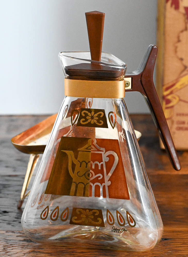 brown and gold coffee carafe on gold warmer stand