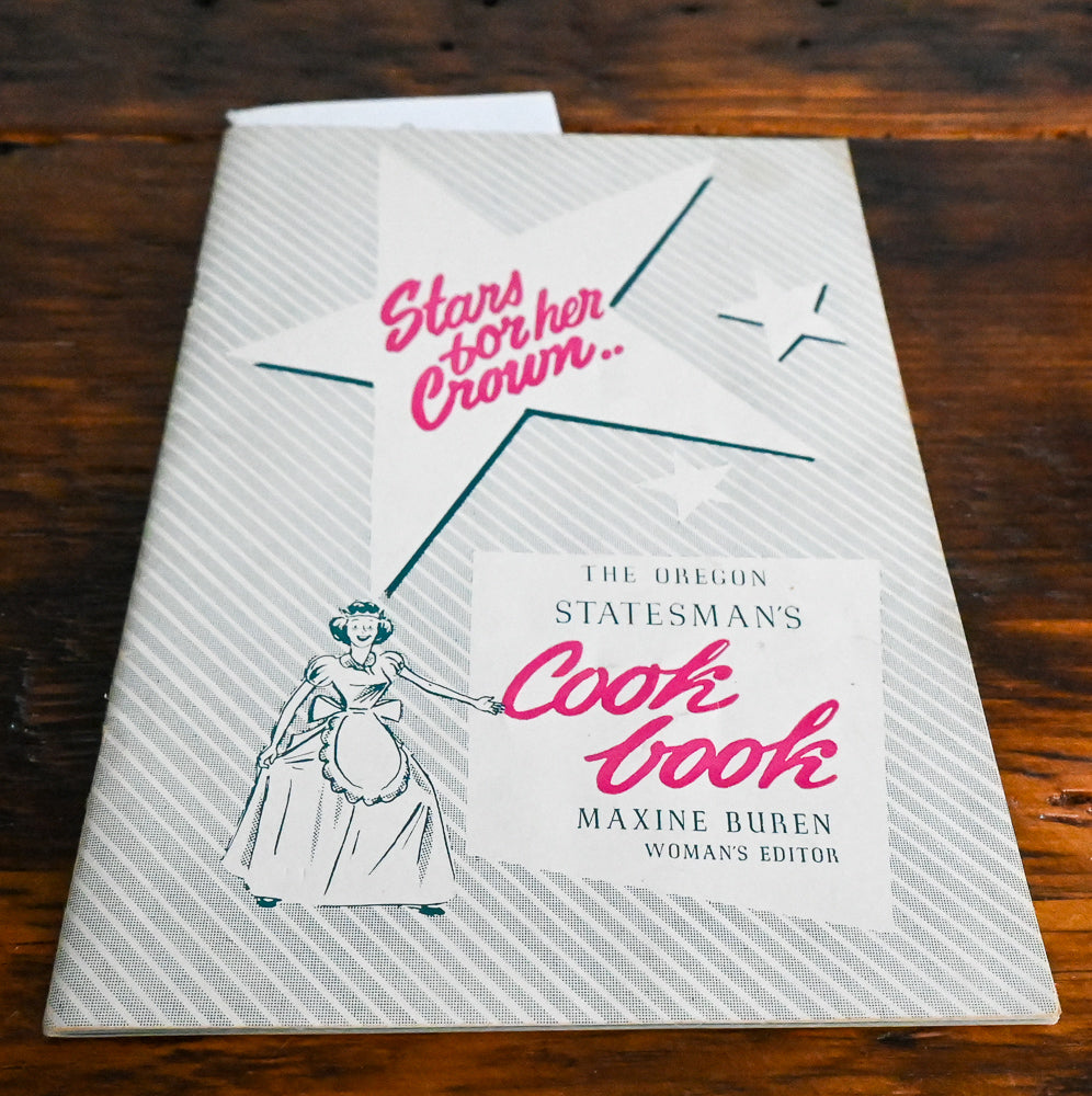 Cover of Stars for Her Crown Cookbook with a lady in an apron and pink words
