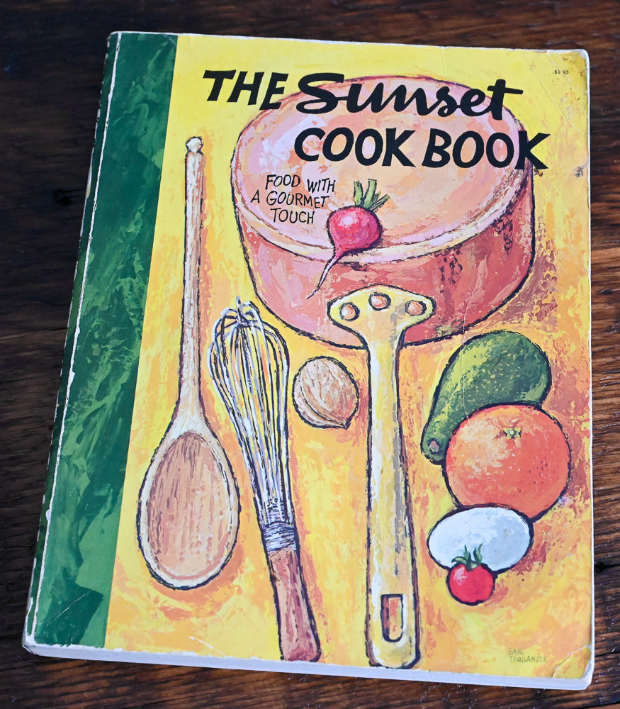 Sunset cookbook with colorful yellow cover, veggies, cooking utensils and saucepan